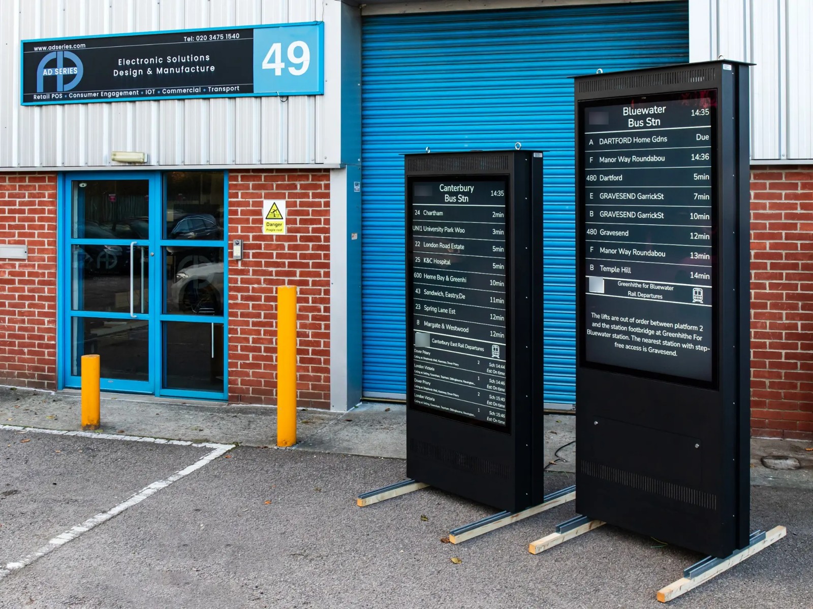 Standard and short 65-inch totems at the AD Series workshop before delivery. Customer logos blurred.